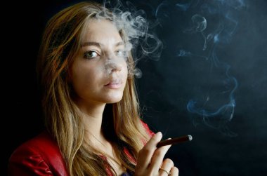 Genç kadın yasaktır cigarillo. Kadın siyah arka plan ile kırmızı ceketli.
