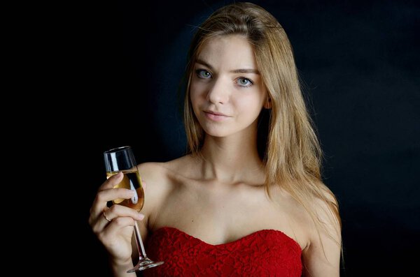 Female model in red dress with glass of champagne in her hand. Evening dress, party.