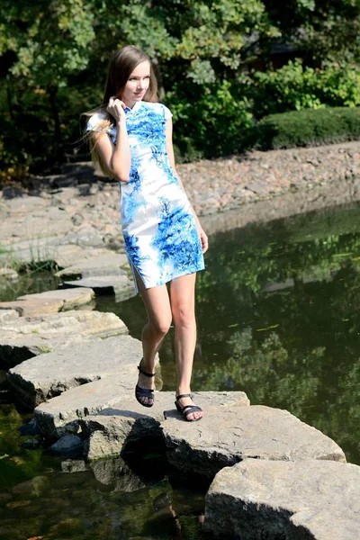 来自波兰的女性模特穿着传统中式连衣裙 蓝色和白色的花朵 妇女摆在亚洲风格的公园 走在岩石之间的水 — 图库照片