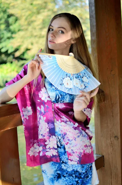 女性模特从波兰穿着传统的中式礼服在蓝色与五颜六色的披肩 妇女摆在亚洲风格公园 — 图库照片