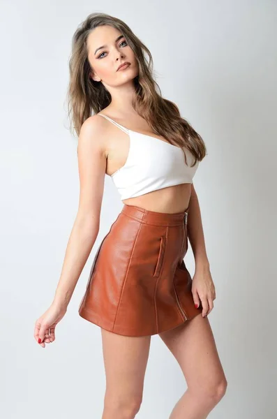 白いトップと茶色の革のスカートに良く造られたモデルです 若い魅力的な女性 — ストック写真
