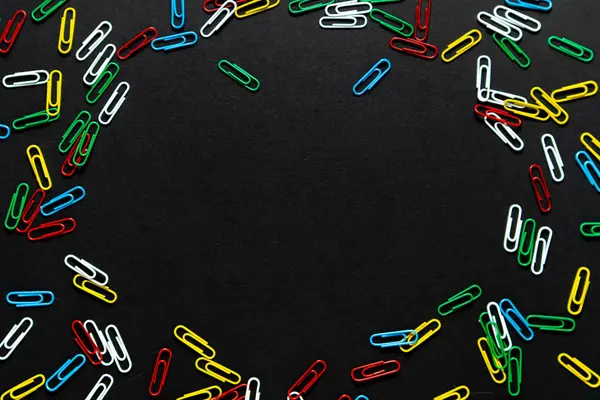 colored paper clips on a black background