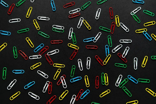 colored paper clips on a black background