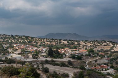 Küçük güzel bir köyün havadan görünümü. Dağların ve fırtına bulutlarının manzarası. Yaz.