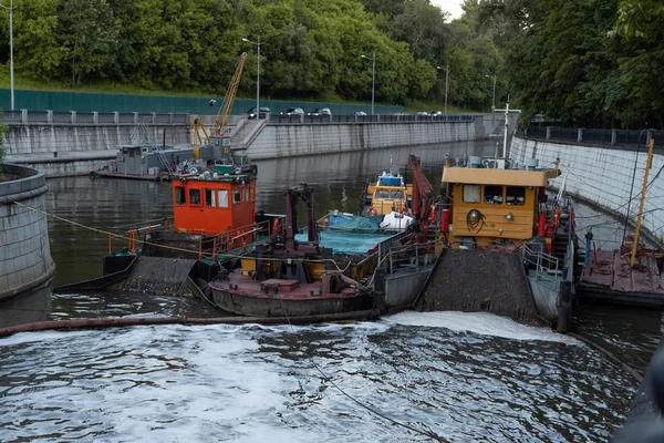 Boats on the river. Waterworks. Garbage collector boat, tugboat, barge and boat with crane.