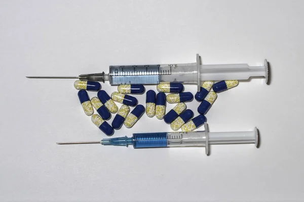 Blue syringes and blue pills. Pills and syringes on white background.