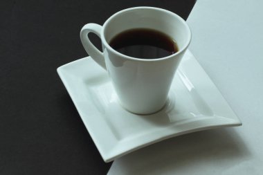 Beyaz ve siyah. Uçan daire üzerinde güçlü aromalı kahve ile beyaz porselen özel fincan arka plan zıt olarak özgün formu. Minimalizm tarzı.