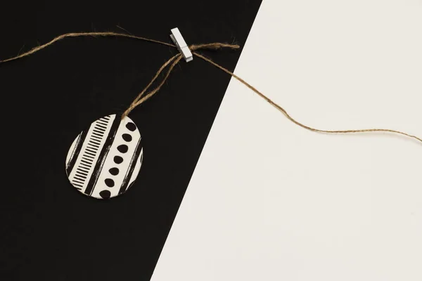 Decorated with napkin for decoupage egg on jute cord with clothespin on contrasting white and black background. Minimalism style.