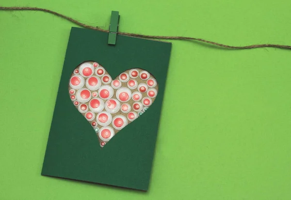 グリーティングの薄緑色の背景付きジュート コードの明るく装飾的な要素の様式化された心で飾られたグリーンの段ボール製の珍しいカード バレンタインの日 母の日 — ストック写真