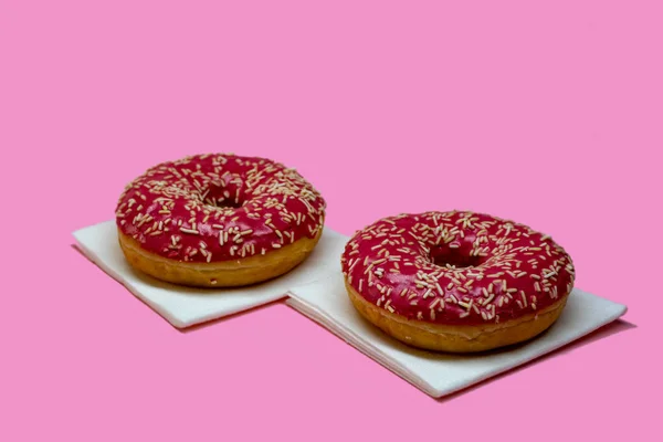 Pembe sırlı çörek pembe bir arka plan üzerinde.