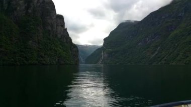 Dağlar ve şelaleler Geirangerfjord. Norveç fiyordu tekne gezisine. Gemide feribot sakin ve bulutlu havalarda çekim. Dağlar ve şelaleler çevreleyen fiyort, görünümünü.