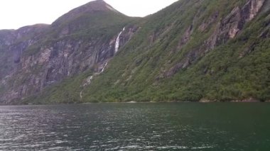 Dağlar ve şelaleler Geirangerfjord. Norveç fiyordu tekne gezisine. Gemide feribot sakin ve bulutlu havalarda çekim. Dağlar ve şelaleler çevreleyen fiyort, görünümünü.
