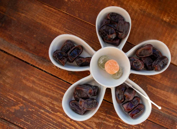 Dates and sweets in a white plate close-up.