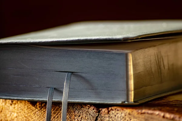 A leather prayer book with silver pages lies on a wooden bench close-up.