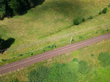 Yeşil doğal çevre, çayırlar, ağaçlar, çimenler, havadan görünümü içinde elektrikli demiryolu.