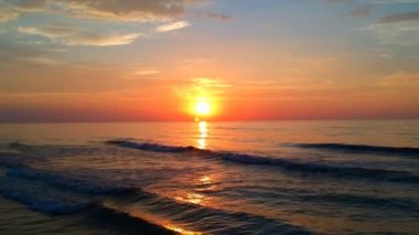 Yavaş yavaş gelen dalgalar deniz deniz ufka günbatımında için aşağı bakıyor