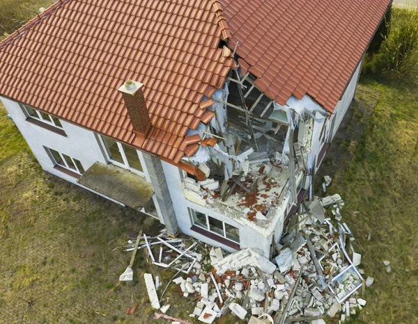 Luftaufnahme eines beschädigten roten Einfamilienhauses nach starkem Wind oder einer Explosion. Loch in Dach und Boden. Trümmer auf dem Boden — Stockfoto