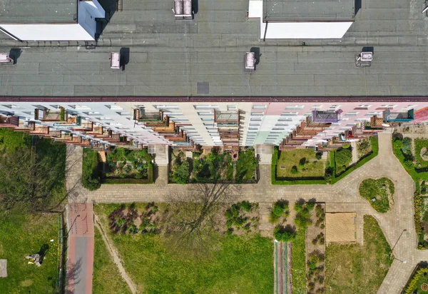 Aerial top down view on rooftop of block flat building with yard, pavements, gardens, multiple windows and balcony