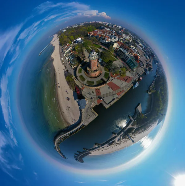 Aerial panoramic tiny planet view on brick brown lighthouse at baltic sea shore with tourists and ship port entrance. — Stock Photo, Image