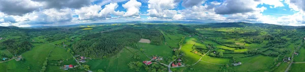 Aerial wide panoramic view on sudety mountains with touristic city in the valley surrounded by meadows, forest and rapeseed fields — Stock Photo, Image