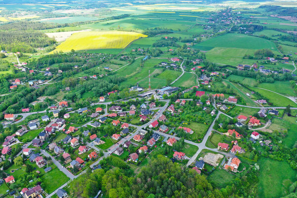 Aerial perspective view on sudety mountains with touristic city in the valley surrounded by meadows, forest and rapeseed fields