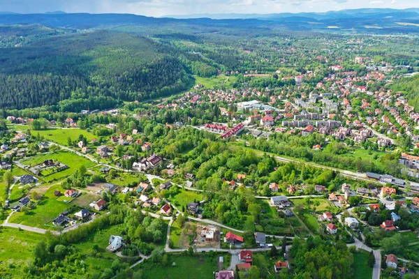 Flygperspektiv Visa på sudety Mountains med turistiska staden i dalen omgiven av ängar, skog och rapsfält. — Stockfoto