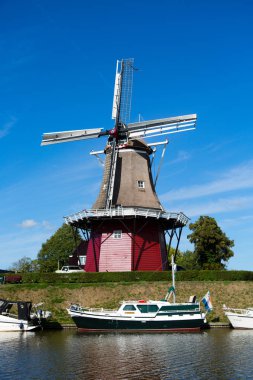 Dokkum, Friesland, Hollanda - 17 Ağustos 2018; Tekneler kanal ve yel değirmeni üzerinde sur şehrin tarihi Dokkum, Friesland, Hollanda