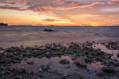 Deniz ve dramatik alacakaranlık gökyüzü Royal Adası'nda kayalık plaj