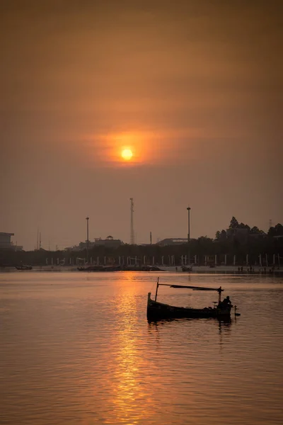 Fishing boat silhouette against sunrise sky at Ancol