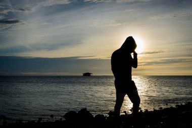 Tek başına duran ve Harapan Adası, Endonezya, arka plan üzerinde güzel gökyüzü ile sahil üzerinde poz bir adam silüeti