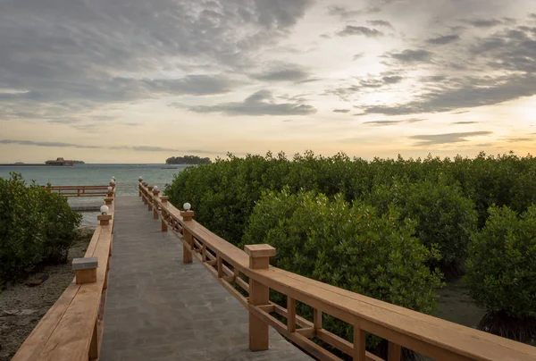 Uma ponte de pedra que leva a um lugar para desfrutar do pôr do sol na Ilha Real, Indonésia. Rodeado por manguezais com belos céus quentes — Fotografia de Stock