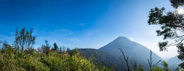 Berrak mavi gökyüzü ile Ghober Hut kamp alanından alınan Papandayan Dağı manzara bir panorama. Papandayan Dağı Garut üzerinde yürüyüş için favori yerden biridir.