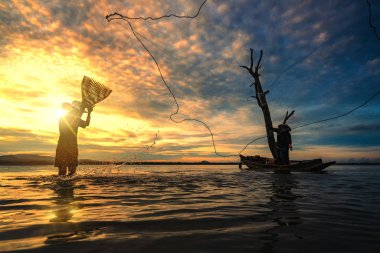 Gündoğumu dönemde Bangpra gölde balık yakalamaya ağları kullanarak balıkçılar.