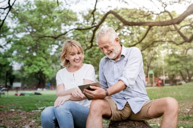 Bir parkta oturan ve tablet kullanma kıdemli çift.
