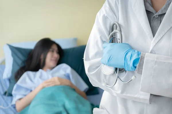 Close up of hand's doctor holding stethoscope and standing on soft blured of patient laying down on bed in hospital