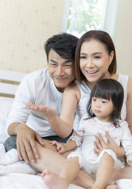 Mutlu aile evde yatakta kızı oyuncaklarla oynamak.