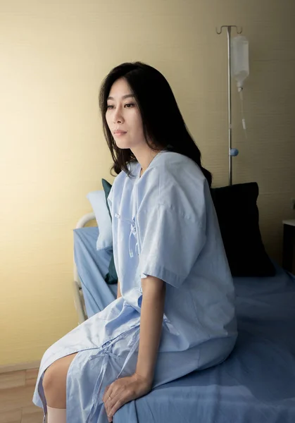Female patient sitting on bed in hospital