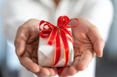 El Beyaz hediye kutu kırmızı kurdele ile tutarak, yakın çekim. 