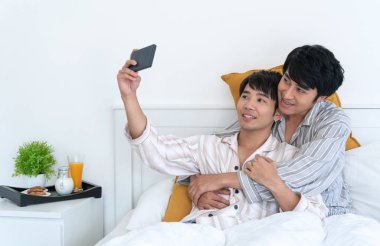 Tatlı Eşcinsel telefon kullanarak çift ve bir selfie evde yatakta al