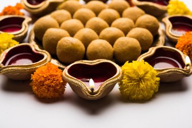 Diwali Rangoli Diya, çiçek ve Besan Laddu veya Laddoo arrabged beyaz arka plan üzerinde seçici odak kullanarak
