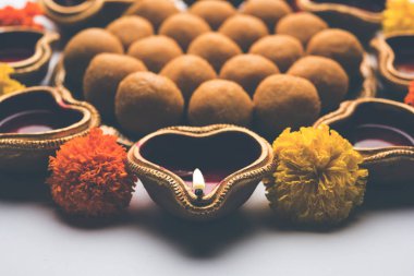 Diwali Rangoli Diya, çiçek ve Besan Laddu veya Laddoo arrabged beyaz arka plan üzerinde seçici odak kullanarak