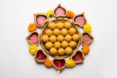 Diwali Rangoli Diya, çiçek ve Besan Laddu veya Laddoo arrabged beyaz arka plan üzerinde seçici odak kullanarak
