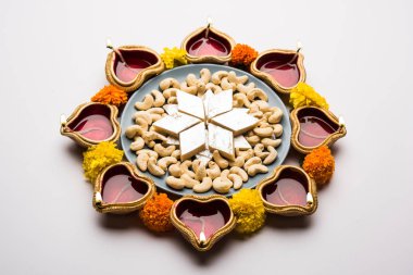 Diwali gıda Rangoli Kaju Katli tatlı kil diya/lamba ve kadife çiçeği çiçek ile birlikte kullanarak dairesel desende, seçici odak düzenlenmiştir.