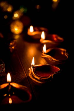 Diwali diya or lighting in the night with gifts, flowers over moody background. Selective focus clipart