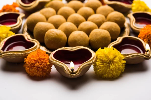 Diwali Rangoli Diya, çiçek ve Besan Laddu veya Laddoo arrabged beyaz arka plan üzerinde seçici odak kullanarak