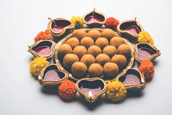 Diwali Rangoli Diya, çiçek ve Besan Laddu veya Laddoo arrabged beyaz arka plan üzerinde seçici odak kullanarak