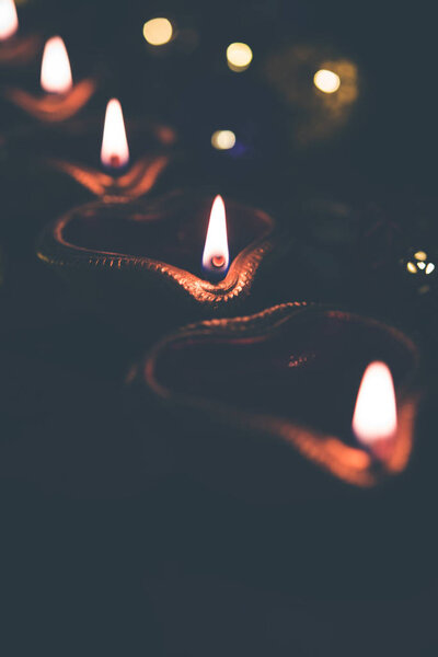 Diwali diya or lighting in the night with gifts, flowers over moody background. Selective focus