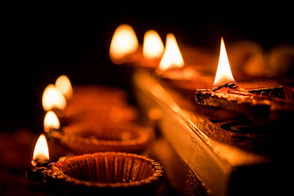 Diwali diya or lighting in the night with gifts, flowers over moody background. Selective focus