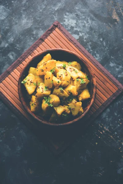 Jeera Aloo is a Indian main course dish which goes well with hot puris, chapatti, roti or dal. served in a bowl over moody background. selective focus