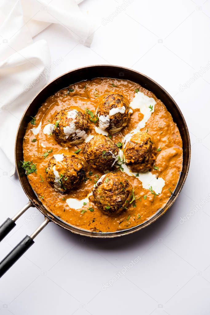Malai Kofta is a Mughlai Speciality dish served in a bowl or pan over moody background. selective focus